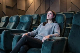 Femme admirative dans un fauteuil de cinéma premium vivant une expérience immersive dans une salle moderne de luxe